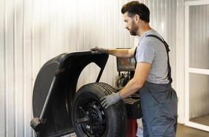 Mechanic mounting a tire on a balancing machine in a workshop photo