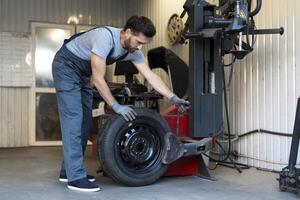 Mechanic mounting a tire on a tire changer machine in a workshop photo