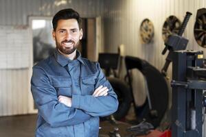 Mechanic smiling with crossed arms in auto repair shop photo