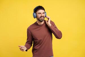 Portrait of smiling, happy middle aged man listening music in earphones, dancing, looking away photo