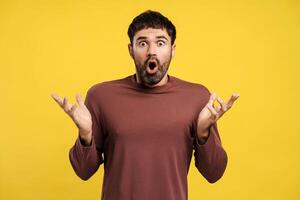 Portrait of excited, shocked bearded man with open mouth looking at camera with open hands photo