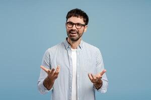 Handsome bearded man, wearing stylish eyeglasses gesturing something explaining looking at camera photo
