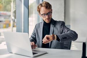 Busy manager checking time working on laptop in office photo