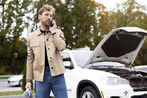 Man calling for assistance with broken down car on roadside photo