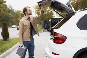 Stylish man holding engine oil checking his trunk before leaving for a road trip photo