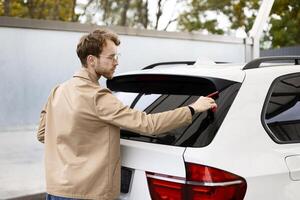 Man cleaning car window with squeegee after washing it photo