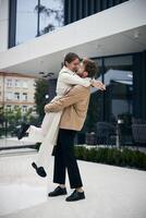 Happy couple embracing in front of modern building photo