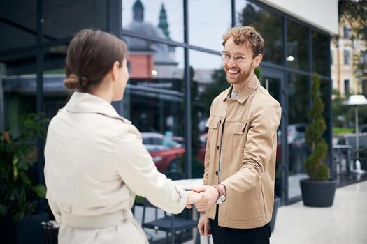 Businessman and businesswoman shaking hands in front of office building photo