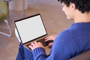 Young man using laptop computer with blank screen for mockup photo