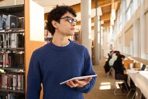 Thoughtful university student looking for book in library photo