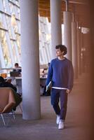 Smiling university student walking in modern library building photo