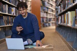 Smiling student using smartphone while studying in library photo
