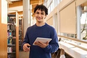 Smiling young man using digital tablet in public library photo