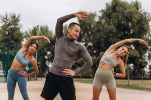 Smiling, attractive sportswomen and sportsman wearing stylish sportwear doing exercises photo