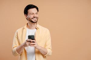 Smiling young man using mobile phone app for online shopping, looking away on copy space photo