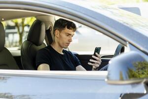 Young man using smartphone while sitting in car photo