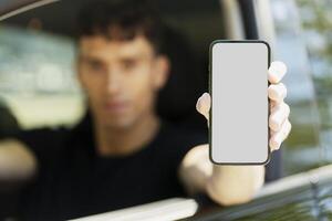 Man driving car showing smartphone with blank screen photo