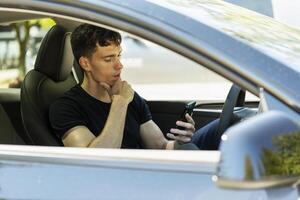 Handsome young man using smartphone app sitting in car photo