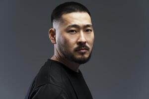 Serious asian man with black short hair and beard looking over shoulder photo