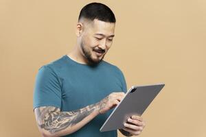 Smiling man using digital tablet on beige background photo