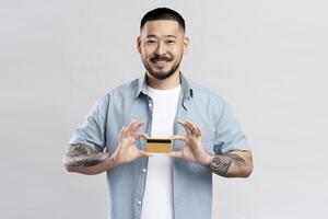 Smiling young man showing credit card on white background photo