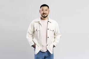Young man smiling with hands in pockets on white background photo