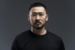 Serious young asian man with a goatee is posing on a grey background photo