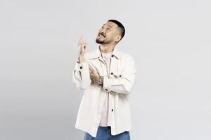 Young man pointing up and smiling on white background photo