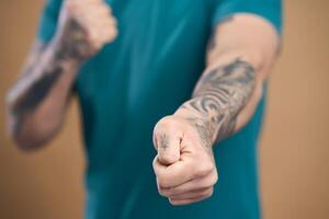 Man showing clenched fist with tattoos on arms photo