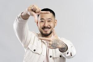 Smiling asian man making a photo frame with his hands