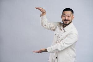 Smiling asian man showing something between hands photo