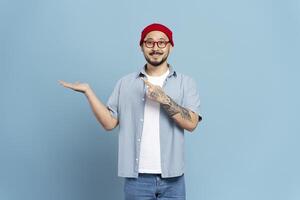 Smiling man pointing at empty hand presenting something on blue background photo