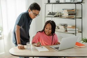 Two students collaborating on school project at home using laptop photo