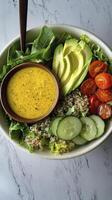 Nutritious salad bowl with quinoa, avocado, and dressing on marble photo