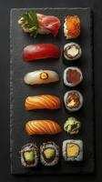 Variety of delicious nigiri and maki sushi rolls displayed on black slate photo