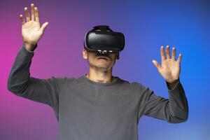 Man experiencing virtual reality with headset on colorful background photo