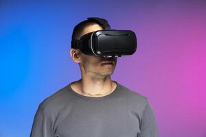 Man experiencing virtual reality using headset on gradient background photo