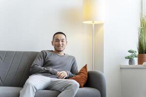 Young man smiling while relaxing on couch at home photo