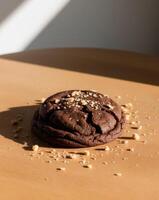 A chocolate cookie on a table with a piece of chocolate on top photo