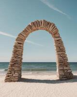A stone arch on the beach with a blue sky photo