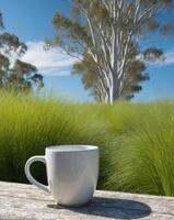 A coffee cup sitting on a wooden table in front of a grassy field photo