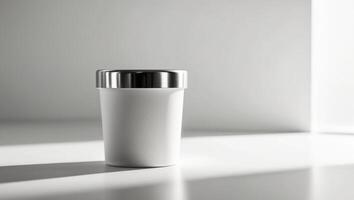 A white cup sitting on a table in front of a window photo