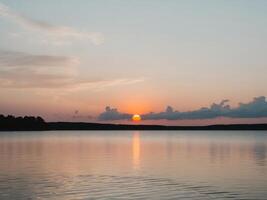 A sunset over a lake with a body of water in the background photo