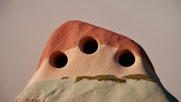 A rock with three holes on top of it photo