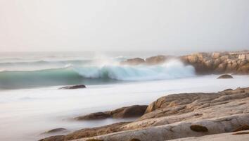 A wave crashes on the rocks at the beach photo