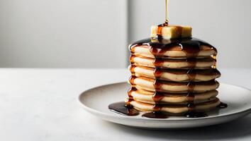 A stack of pancakes with syrup and butter being poured over them photo