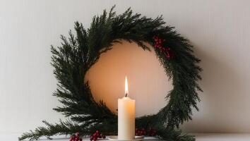 A candle is lit in front of a wreath of evergreen branches photo
