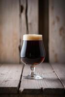 A glass of dark beer sitting on a wooden table photo