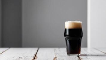 A dark beer is sitting on a wooden table photo