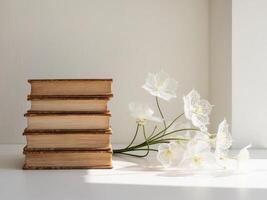 A stack of books and a white flower on a table photo